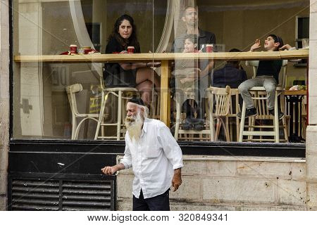Jerusalem, Isaril, 04.05.2018. A Beggar Old Man Asks For Alms In The Background Of A Restaurant Wher