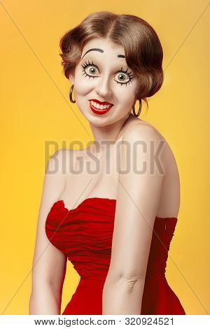 Fun Young Woman With Vintage Pinup Makeup Making Dolly Face Looking At Camera, Yellow Background