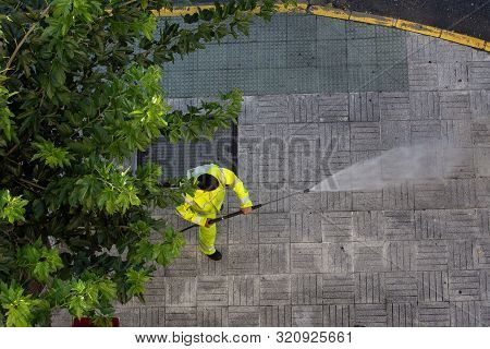 Worker Cleaning The Street Sidewalk With High Pressure Water Jet