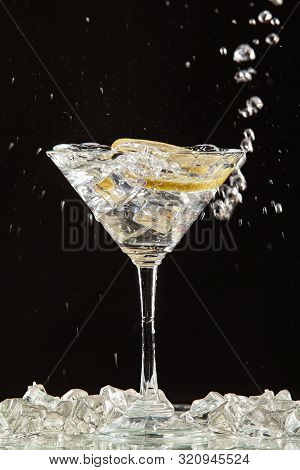 Glass Of Water, Lemon And Watersplashes On A Black Studio Background
