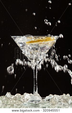 Glass Of Water, Lemon And Watersplashes On A Black Studio Background