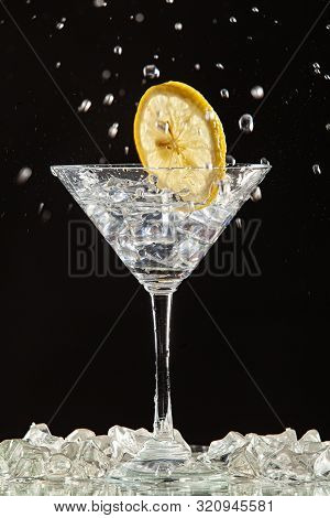 Glass Of Water, Lemon And Watersplashes On A Black Studio Background