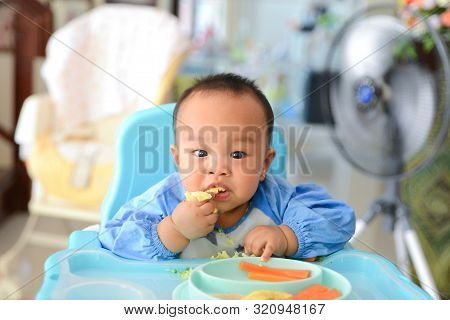 Asian Baby Boy 6 Months Old Eating With Baby Led Weaning (blw) Method, Self-feeding