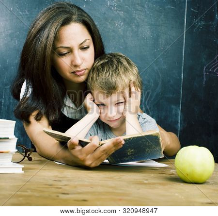 Little Cute Boy In Glasses With Young Real Teacher, Classroom Studying At Blackboard School Kido