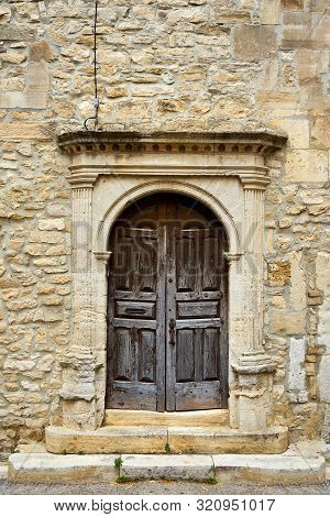 Old Church Porch With Wooden Door And Stone Wall At Barjac Occitanie France