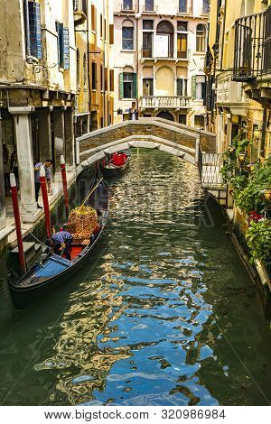 Venice, Italy - May 26, 2019: Unidentified People At Traditional Gondola In The Narrow Canal In Veni