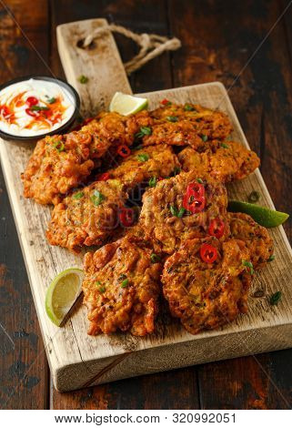 Indian Takeaway Food, Spicy Onion Bhajis Served With Chili Yoghurt Dip And Lime Wedges On Wooden Boa