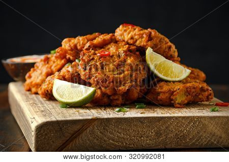 Indian Takeaway Food, Spicy Onion Bhajis Served With Chili Yoghurt Dip And Lime Wedges On Wooden Boa