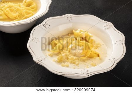 Tortellini Served With Broth And Cream Sauce And Parmesan Cheese, Italian Food On A Black Background
