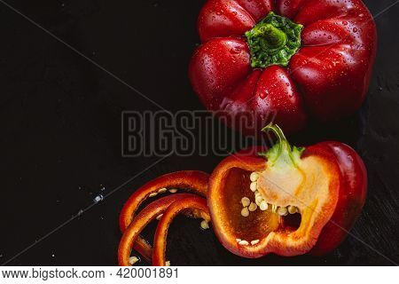 Fresh Red Bell Pepper And Slice On Black Background. Top View Tropical Abstract Background. Cloe Up 