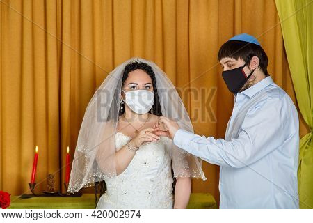 During A Chuppah Ceremony At A Jewish Wedding In A Synagogue, The Groom Puts A Ring On The Bride's I
