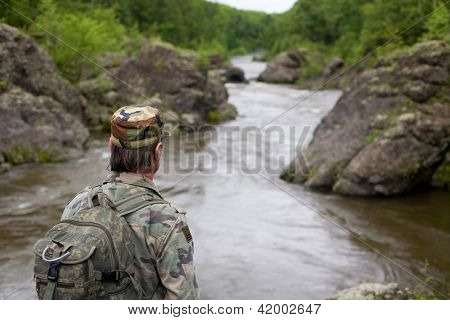 Tramp v maskovací oděv na skalnatém břehu horské řeky. Rusko. Primorskiy kray.