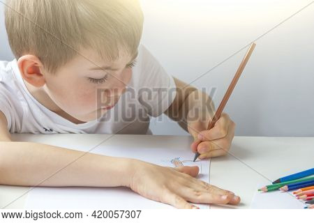 Focused Preschooler Little Boy 5-6 Years Painstakingly Draws Drawing By Pencil. Doing Homework, Draw