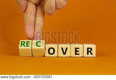 Time To Recover Symbol. Businessman Turns Wooden Cubes And Changes The Word 'over' To 'recover'. Bea