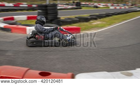 A Panning Shot Of A Racing Kart As It Circuits A Track.
