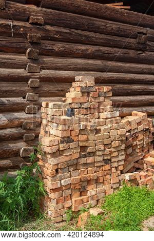 Old Fireclay Bricks Are Piled Up Against A Log Wall. Vertical Image.