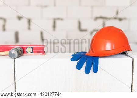 Builder Tools Lays Aerated Concrete Block At A Construction Site. Objects. Hemlet, Gloves, Water Lav