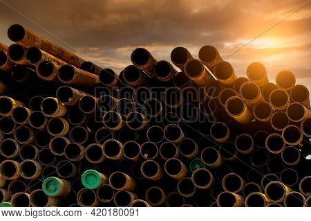 Pile Of Old Rusty Round Metal Industrial Pipe. Steel Pipe Stack During Sunset. Industrial Material. 