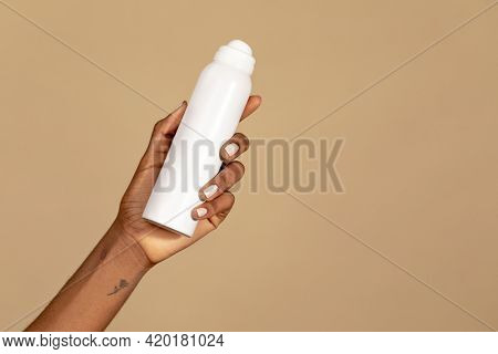 Black woman holding an unlabeled white spray bottle