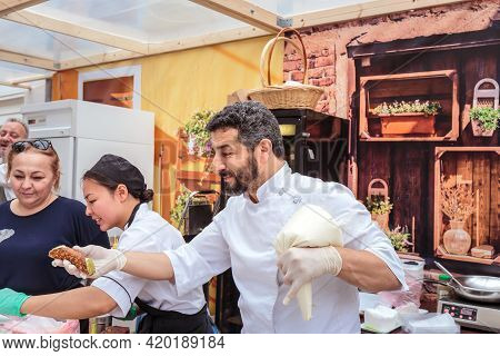 Moscow, Russia, July 13, 2019: An Italian Chef In Uniform Fills A Cream Cone With Cannoli Siciliani.