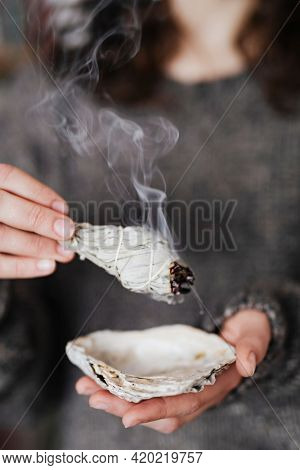 Woman burning sage smudge to cleanse the house
