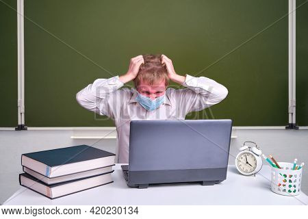 Angry Sudent In A Classroom With A Red Face Tearing His Hair With His Hands At The School Blackboard