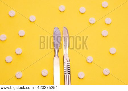 Two Iron Chrome Surgical Scalpels Lie On A Yellow Background Surrounded By White Polka Dot Tablets. 