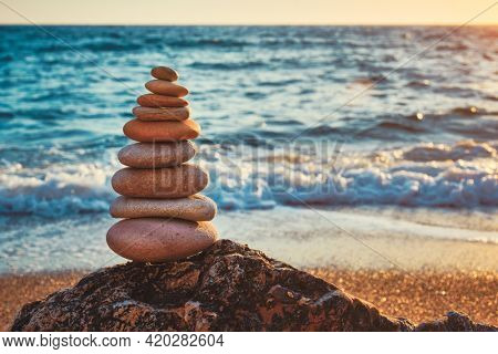Concept of balance and harmony. Cairn stack of stones pebbles cairn on the beach coast of the sea in the nature on sunset. Meditative art of stone stacking
