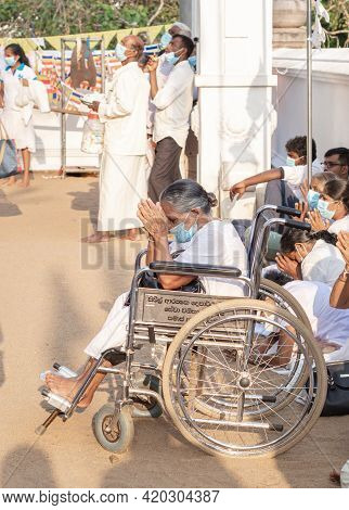 Anuradhapura, Sri Lanka - 03 31 2021: Old Devotee In A Wheelchair Worshipping Both Hands On Her Fore