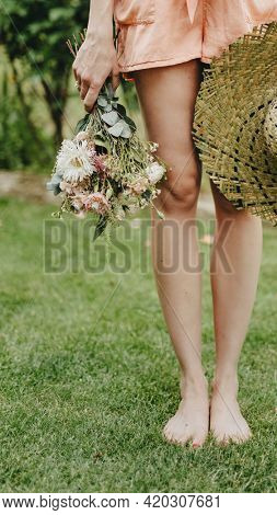 Woman in an orange jumpsuit with a bouquet of flowers