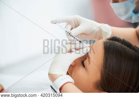 Woman Getting A Dermal Filler Injection Into The Glabellar Line