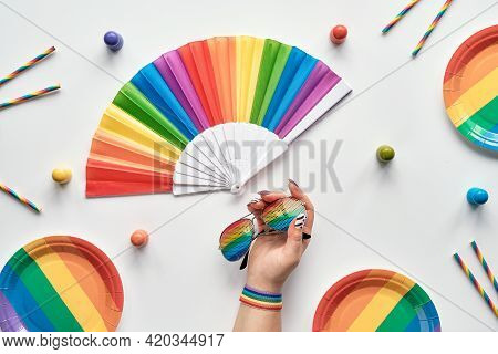 Lgbtq Community Pride Month Rainbow Concept Flat Lay. Hand With Ribbon And Sun Glasses. Rainbow Fan,