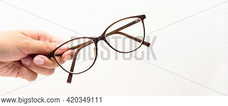 Human Hand Holding Modern Glasses On White Background. Vision Concept. Way To Improve Eyesight. High