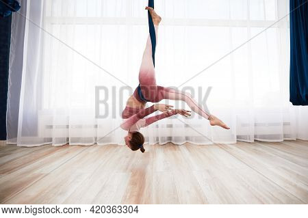 Cheerful Sporty Woman Wearing Top And Leggings Performing Anti-gravity Yoga Exercise At Spacious Hea