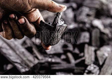 Hand Holding Piece Of Charcoal, With Background. Dirty Coal Emitter Hand
