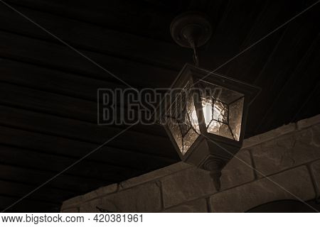 Vintage Glowing Street Lamp Hang On Wooden Ceiling In Garden Yard In Selective Focus. Dark Night Old