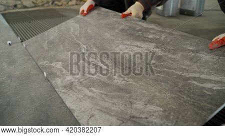 Adhesive Solution For Gluing Ceramic Floor Tiles. Professional Worker Gluing Decorative Tiles To The