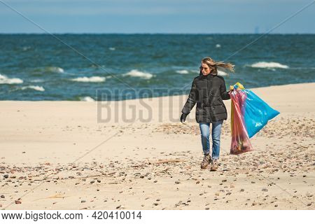 Nida, Lithuania - May 8 2021: Beautiful Volunteer Girl Collecting Plastic Trash Rubbish Garbage On T