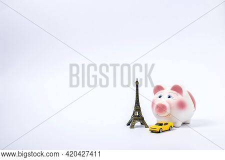 Travel Or Vacation Money Saving Concept. Pink Piggy Bank With Car And Eiffel Tower Isolated On White