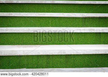 Abstract Concrete Walkway Is Descending In Steps. Concrete With Green Artificial Grass Background. B
