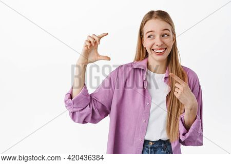 Blond Woman Holding Something Small And Finy. Girl Laughing While Pointing At Her Hand Showing Littl