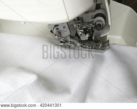The Overlock Sewing Machine Sews White Fabric. Garment Industry