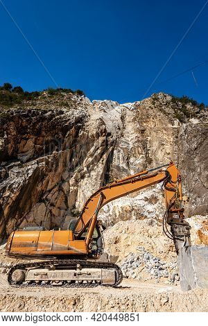 Orange Tracked Excavator With Jackhammer In A White Marble Quarry. Apuan Alps (alpi Apuane), Massa A