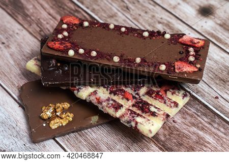 Different Kinds Fof Chocolate Bars Stacking On Vintage Wooden Background. Dark One, Milk And White, 