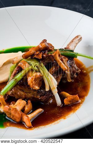 Roasted Lamb Chops With Chanterelles And Vegetables On Decorated Table