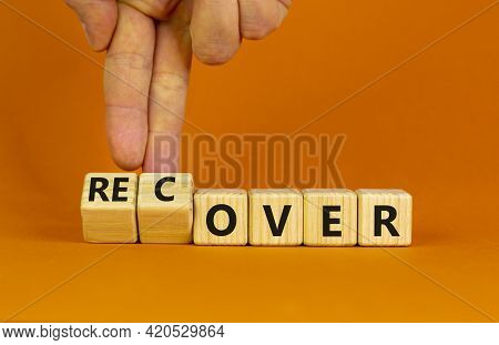 Time To Recover Symbol. Businessman Turns Wooden Cubes And Changes The Word 'over' To 'recover'. Bea