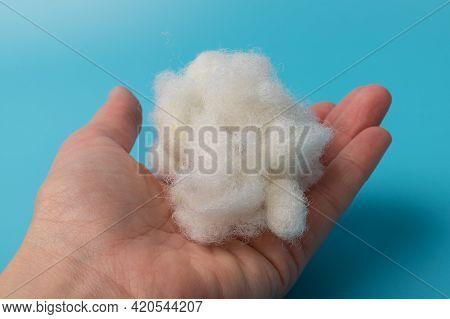 White Air Sintepon In Hand. Type Pillow Material. Sintepon Filler On Blue Background, Soft Texture