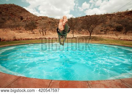 Man jums into the swimming pool in african camping