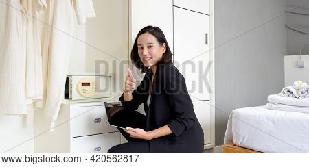Asian Businesswoman In Black Suit Sitting With Tablet Computer In Her Hand. The Hotel Manager Verify