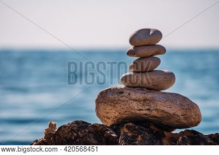 Pyramid Stones On The Seashore On A Sunny Day On The Blue Sea Background. Happy Holidays. Pebble Bea